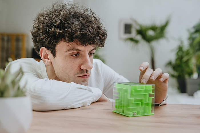 Businessman playing with cube maze at desk in office