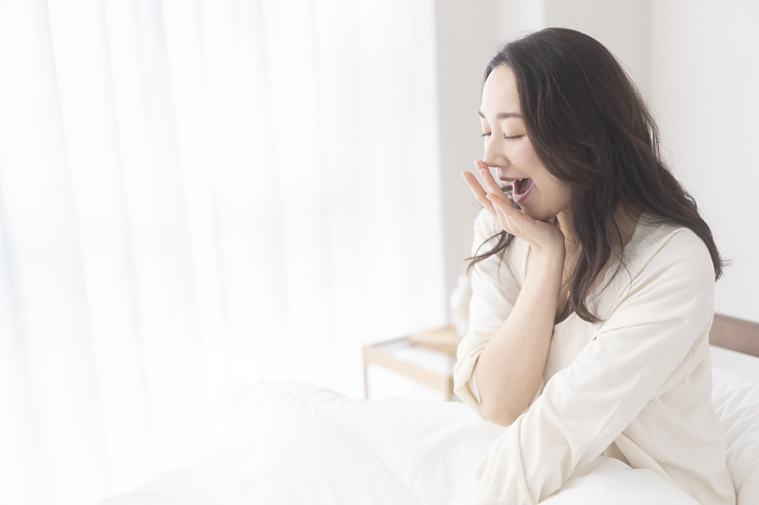 Japanese woman yawning in bed in the morning.
