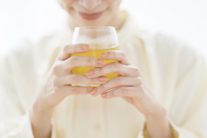 A Japanese woman sniffs the aroma of a drink in a glass.