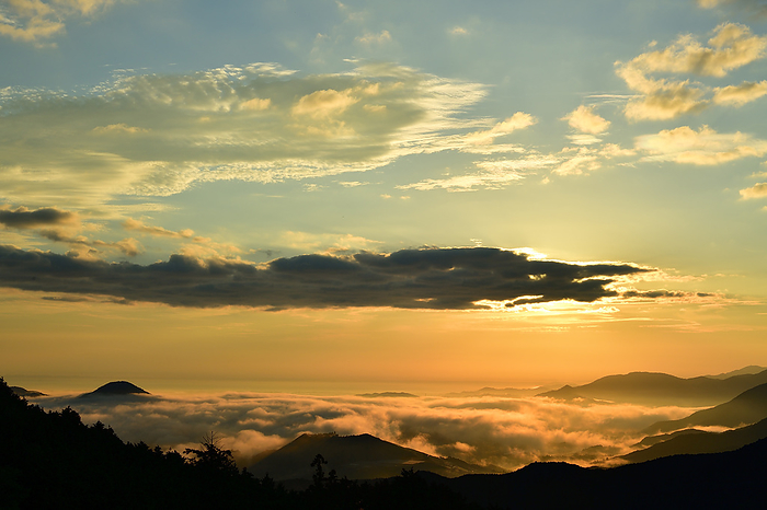Sunrise over Ise Bay, Mie Prefecture, Japan: Sea of clouds in the Miya River basin tinted by the morning glow. Morning in Tokai. The Shishigatake ridge line floats in silhouette. The Miya River basin is a sea of thick clouds. The sunrise from between the clouds fluttering in the summer colored sky.