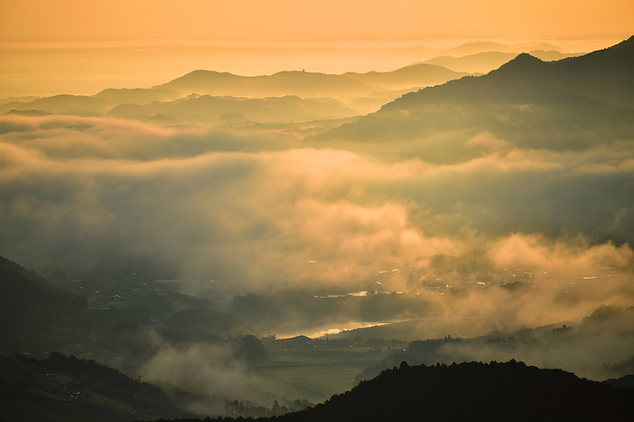 Sunrise over Ise Bay, Mie Prefecture, Japan: Sea of clouds in the Miya River basin tinted by the morning glow. Morning in Tokai. The Shishigatake ridge line floats in silhouette. The Miya River basin is a sea of thick clouds. The sunrise from between the clouds fluttering in the summer colored sky.