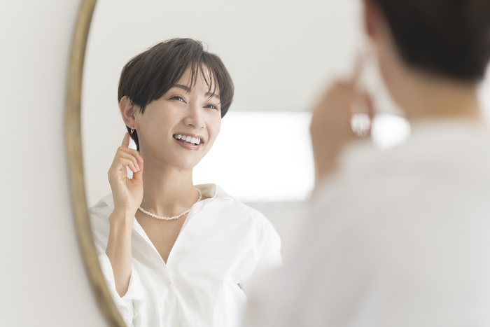 Japanese woman checking her appearance in front of a mirror (People)