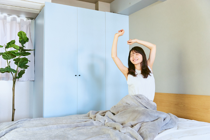 A Japanese woman in her 20s or 30s waking up refreshed from a good night's sleep on a holiday morning in her one bedroom (People)