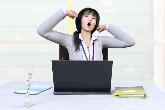 Female employee yawning loudly while working at her desk in her office
