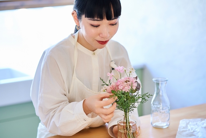 Young Japanese woman enjoying displaying flowers in a vase (People)