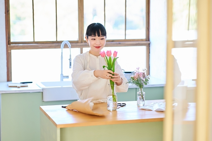 Young Japanese woman enjoying displaying flowers in a vase (People)
