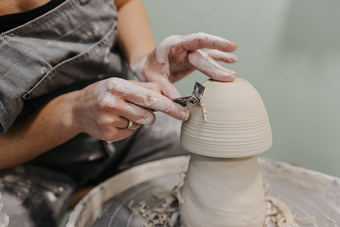 Close up of woman working on pottery at pottery wheel in studio, Sioux Falls, South Dakota, United States, by Cavan Images / Ashley Wegh