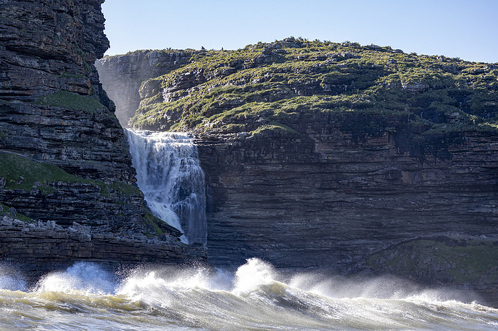 Waves breaking on the coast, a waterfall in the background, South Africa, Eastern Cape, Port Saint Johns NU, by Cavan Images / Raffi Maghdessian