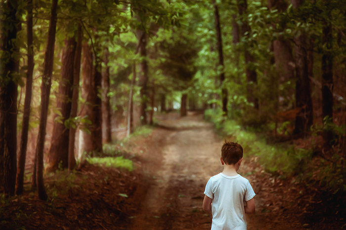 Boy walking along a wooded path with sunlight streaming in, Tulsa, Oklahoma, United States, by Cavan Images / Kristen Ryan