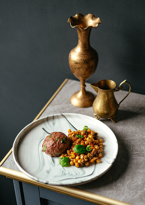 beef patty on a plate with a side dish of chickpeas and sauce, Berlin, Berlin, Germany, by Cavan Images / Aleksandr Kuzmin