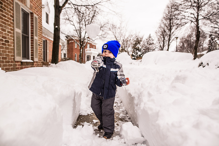 Preschooler outside in snow gear throws snowball at camera, Reading, Pennsylvania, United States, by Cavan Images / Liz DeGroff