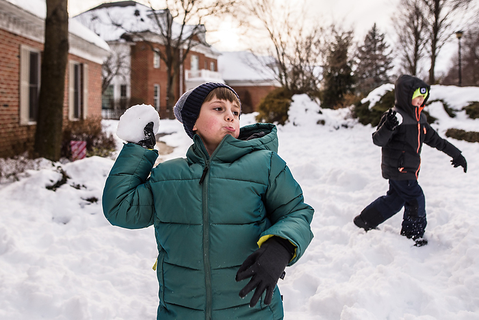 Boys in snow gear get ready to throw snowballs in yard, Reading, Pennsylvania, United States, by Cavan Images / Liz DeGroff