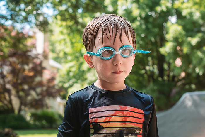 Close portrait of wet, cross-eyed young boy wearing goggles, Reading, Pennsylvania, United States, by Cavan Images / Liz DeGroff