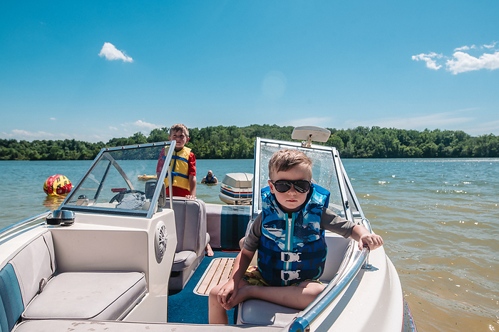 Young boy sits in boat with life jacket and sunglasses, Reading, Pennsylvania, United States, by Cavan Images / Liz DeGroff
