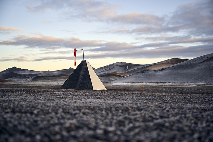 Pyramid with windsock on snowy land against mountains, Selfoss, Iceland, by Cavan Images / Oscar Bjarnason