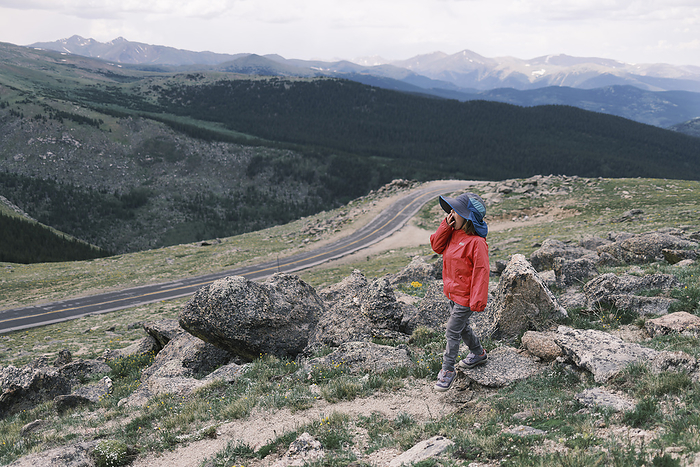 Young girl hiking on a mountain ridge, enjoying the scenic beauty, Denver, Colorado, United States, by Cavan Images / Patrick Lienin