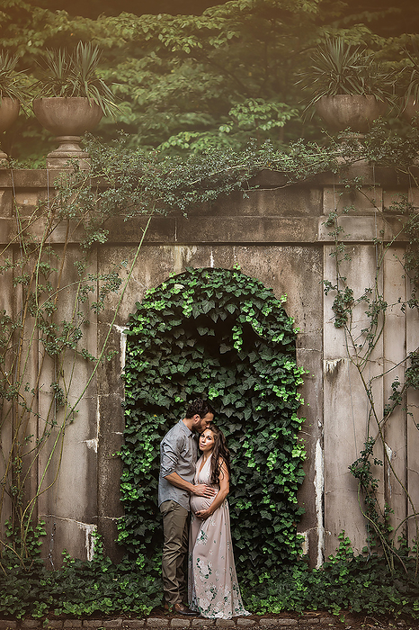 Expectant couple embracing in front of an ivy wall, Atlanta, Georgia, United States, by Cavan Images / Jamie Sapp