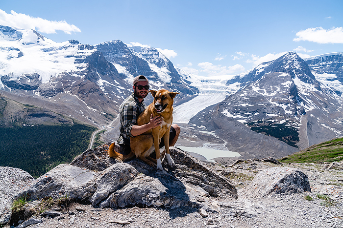 Owner Poses For Photo With Handsome Dog, Jasper, Alberta, Canada, by Cavan Images / Ryan Richardson