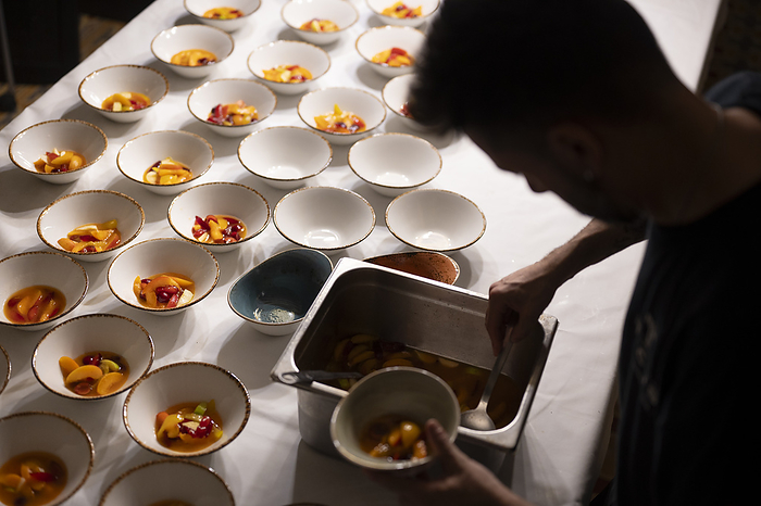 Silhouette of a chef plating many desserts on a table., Torrelavit, Catalunya, Spain, by Cavan Images / Óscar Lopera Martos