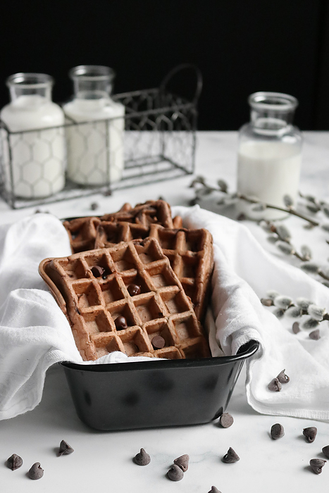 Chocolate Waffles in a black baking pan and milk in the background, Seattle, Washington, United States, by Cavan Images / ELENA LEVCENCO