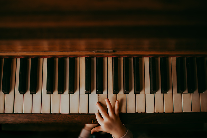 A child's hands playing an old piano, Eaton, Ohio, United States, by Cavan Images / Chelsea Crosier
