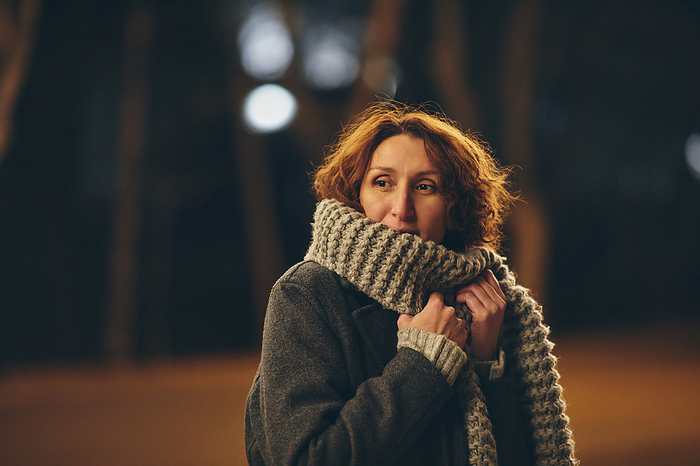 woman hiding her face in a scarf in the night city, Chișinău, Chisinau, Moldova, by Cavan Images / Elena Perevalova