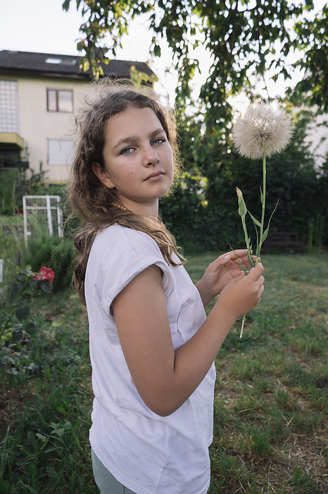 teenage girl with a dandelion flower in her hands in the summer garden, Mainz, Rhineland-Palatinate, Germany, by Cavan Images / Alena Kinderfotografin