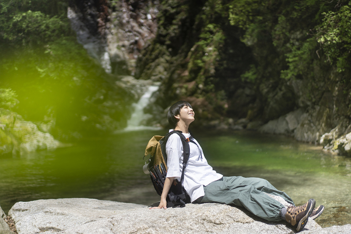 A Japanese woman rests on a rocky canyon during a summer trek (People)