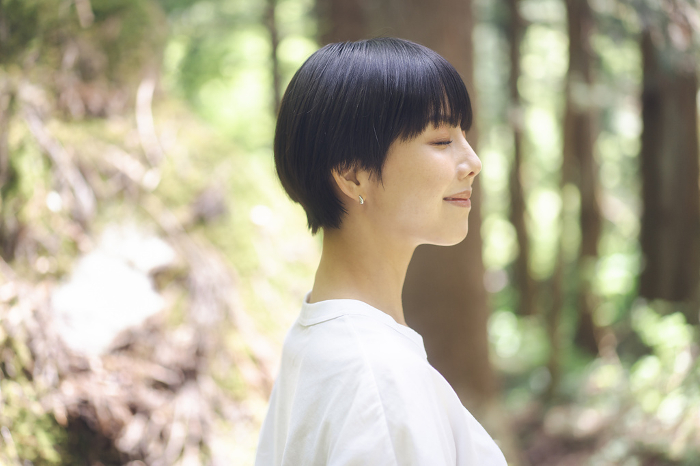 Young Japanese woman closing her eyes in the forest (People)