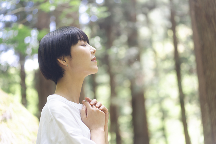 Japanese woman taking a deep breath in the forest (People)