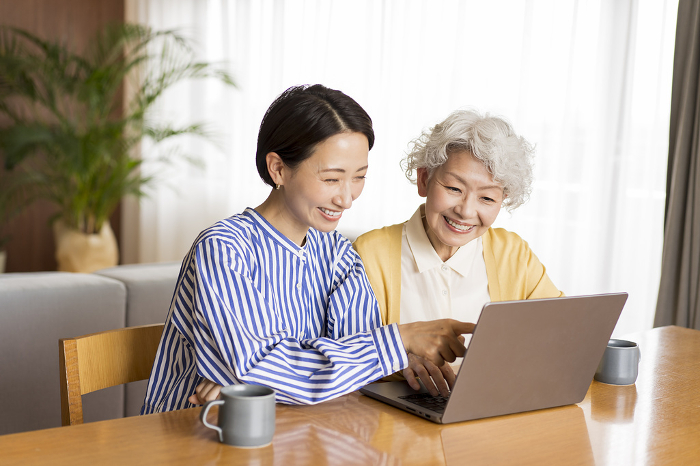 Senior Japanese woman being taught how to use a computer (People)