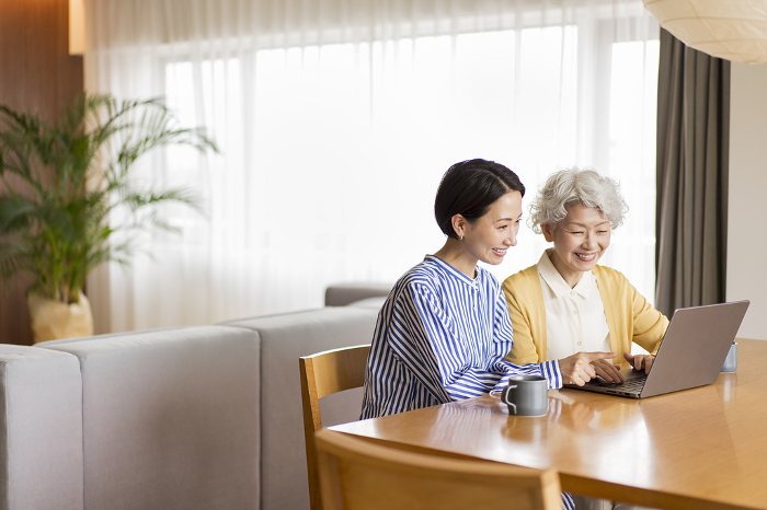 A senior Japanese woman being taught to use a computer by her family (People)