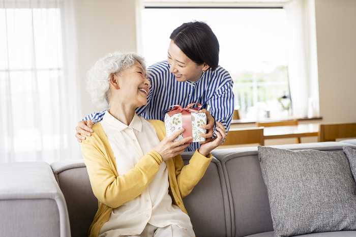 Woman giving a gift to a Japanese senior woman (People)