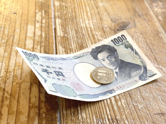 Thousand-yen bill and 500-yen coin on a wooden table