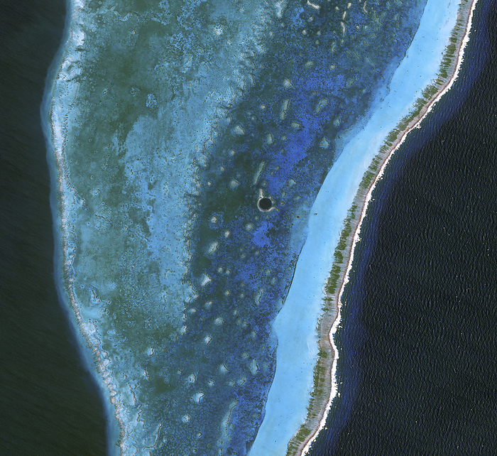Great Blue Hole in Belize, satellite image Satellite image of the Great Blue Hole  at centre  in Belize. This is a vertical cave located in Belize s Lighthouse Reef Atoll. It measures roughly 300 metres across and 125 metres deep, making it a popular diving destination. It likely formed during the last Ice Age, when global sea levels were much lower. The marine sinkhole contains many geologic features, including limestone stalactites and stalagmites. The shallow waters and pale corals in the Lighthouse Reef Atoll create varying shades of blue green, with the ring of lighter colour surrounding the Hole caused by elevated coral. To the east, a broad band of aquamarine indicates an area of especially shallow water along the reef s margin. The reef crests the ocean surface along its easternmost edge, where breaking waves from the Caribbean Sea form a jagged line of white. Image obtained on 24 March 2009 by NASA s Advanced Land Imager  ALI  on the Earth Observing 1 satellite  EO 1 ., by AIRBUS DEFENCE AND SPACE   SCIENCE PHOTO LIBRARY