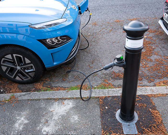 Electric car at pavement charging point Electric car plugged into charger on a suburban street., by ROBERT BROOK SCIENCE PHOTO LIBRARY