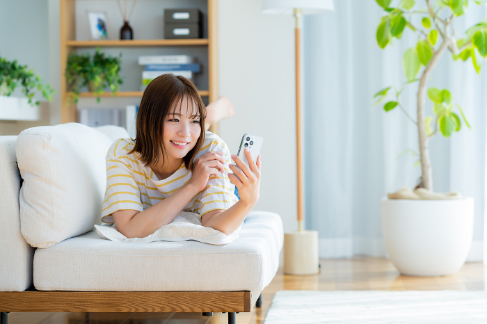 Young Japanese woman operating a smartphone in her room (People)