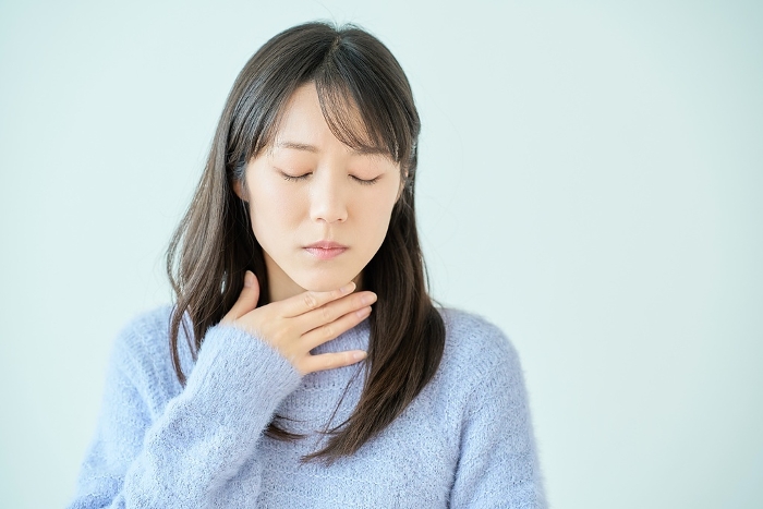 Young Japanese woman feeling discomfort in her throat.
