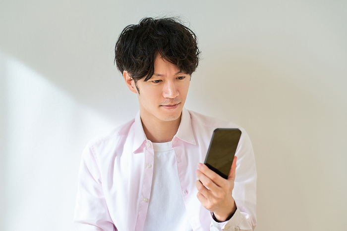 Young Japanese man holding a smartphone (People)