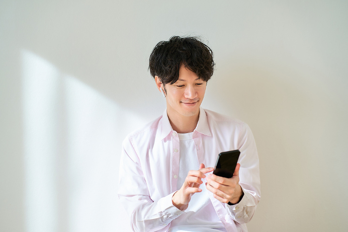 Young Japanese man holding a smartphone (People)
