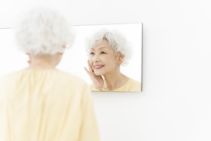 Japanese senior woman taking care of her skin in the mirror (People)