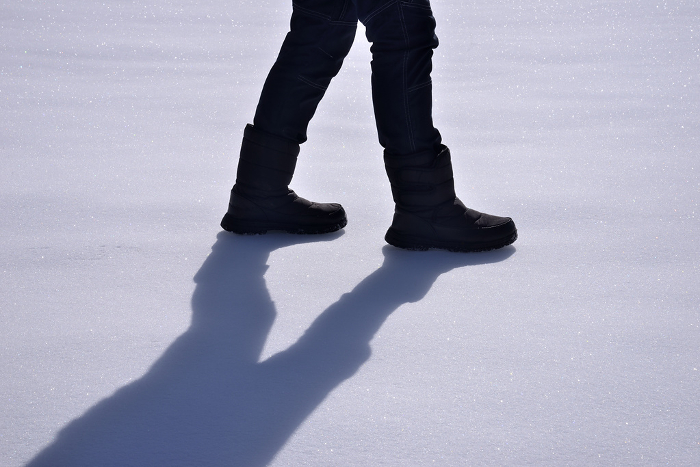 Man's feet walking on snow