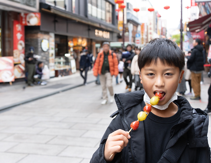 Boy eating strawberry candy in Yokohama Chinatown
