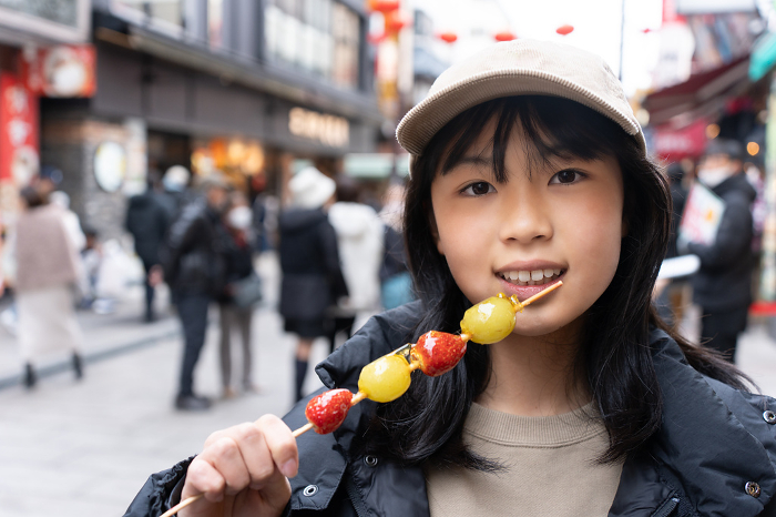Teenager eating strawberry candy in Yokohama Chinatown