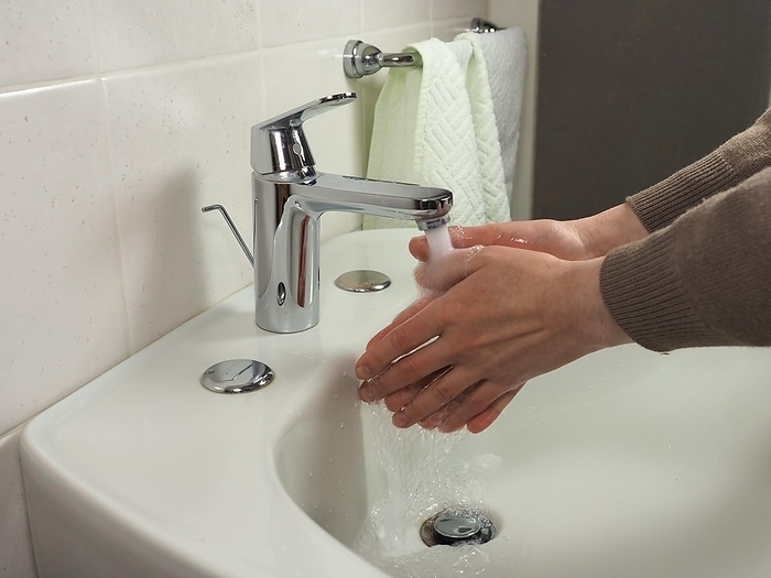 Unrecognisable man washing hands, by Claudio Divizia