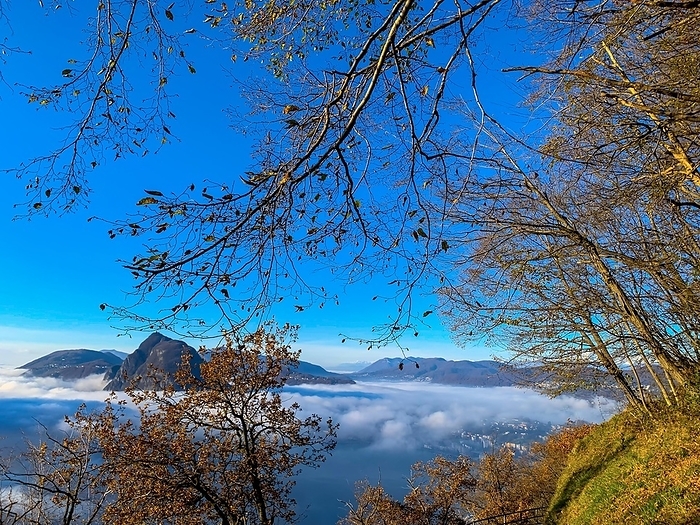 Mountain Peak San Salvatore Above Cloudscape with Sunlight and Clear Sky in Lugano, Ticino in Switzerland, by Mats Silvan