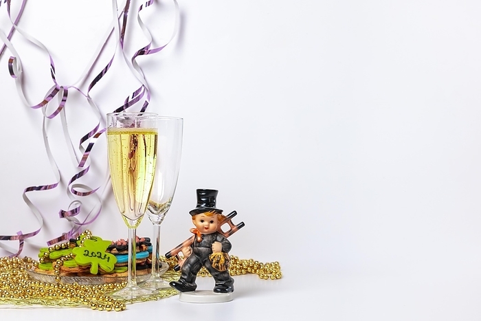 Two champagne glasses, one filled, lucky charm for New Year, white background, copy room, by Lucas Seebacher
