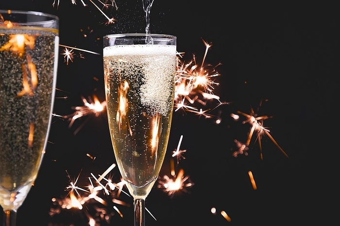 Two champagne glasses, pouring champagne, fireworks, dark background, copy room, by Lucas Seebacher