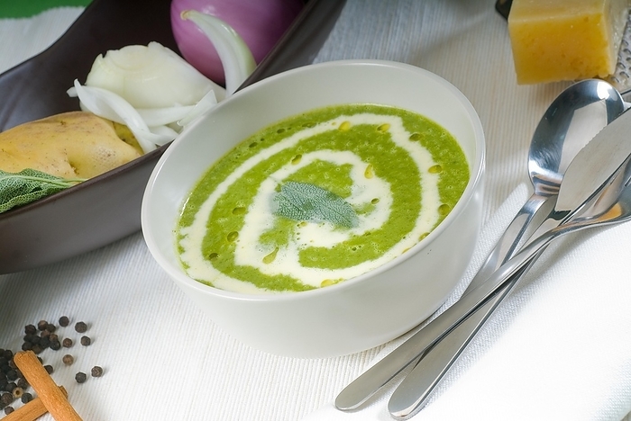 Fresh spinach soup on a white bowl with sage and cream on top, by keko64