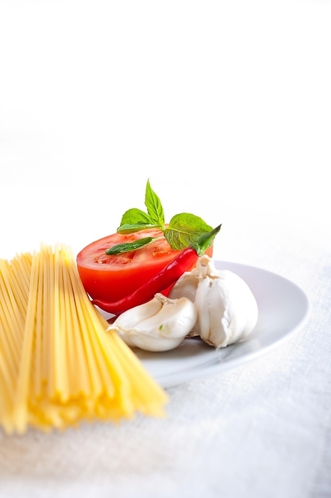 Italian spaghetti pasta tomato raw ingredients basil garlic and red chili pepper, by keko64